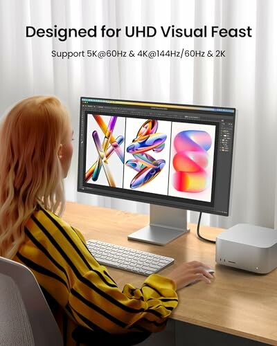 Woman working on a computer with vibrant designs displayed on a monitor, emphasizing UHD support.